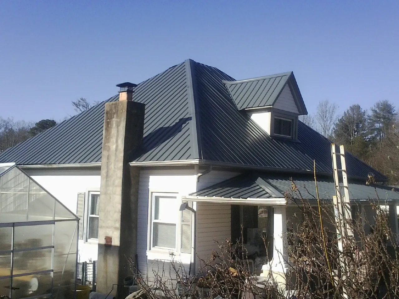 Dark blue standing seam metal roof on a white farmhouse with dormer — Slate & Tile Roof Repair by Roofing Brothers in Walhalla