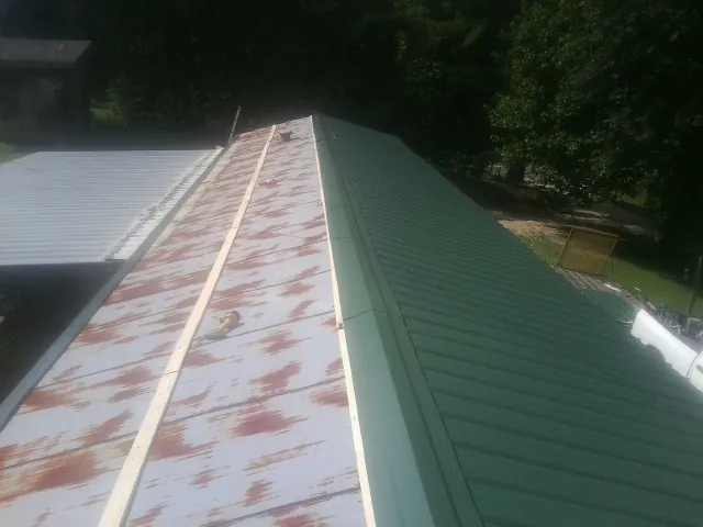 Old rusted panels beside newly installed green metal roofing — Wind Damage Roof Repair by Roofing Brothers in Walhalla