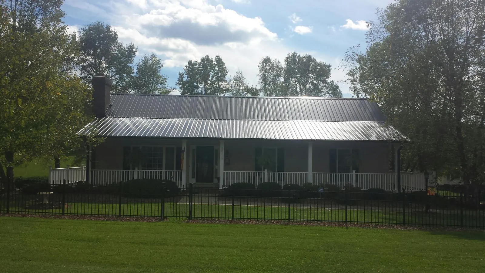 Gray metal roof on a brick ranch with a full width front porch — Gutter Guard Installation work by our crew in Walhalla