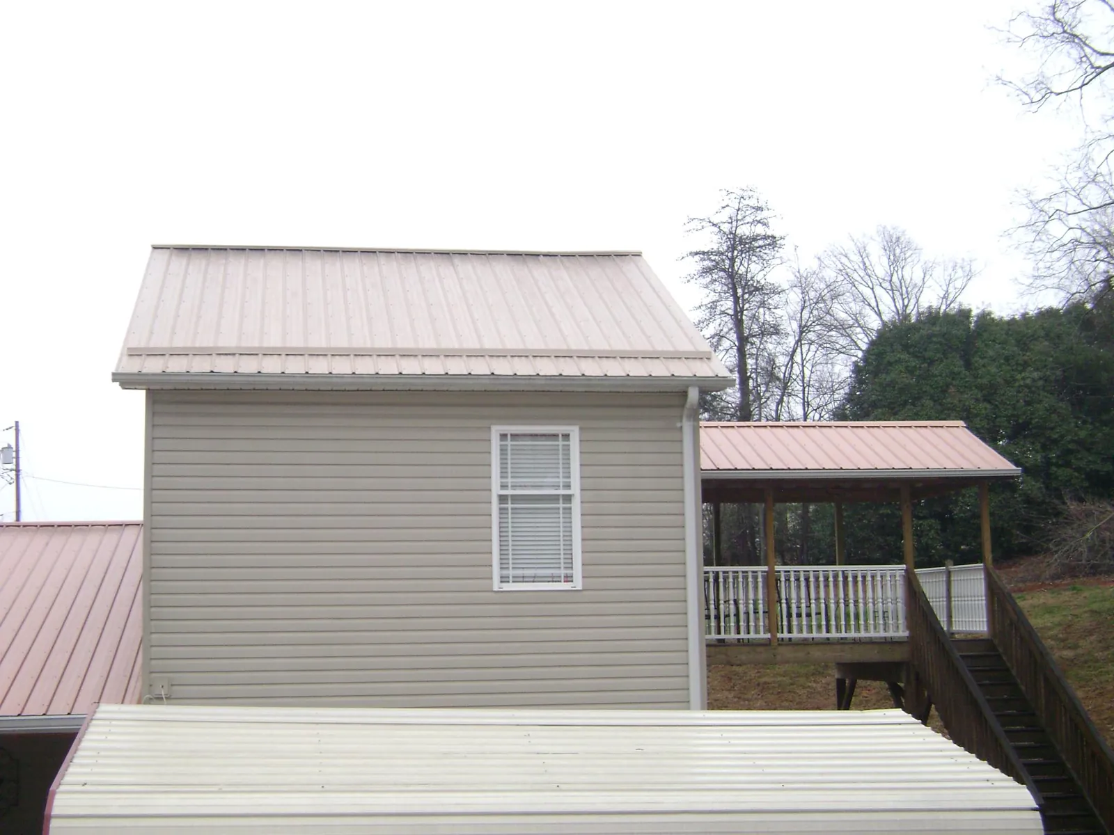 Tan metal roofs on a two story addition and attached porch, from a Roof Replacement job in Walhalla